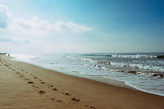 Serene Beach Landscape with Footprints in Sand and Ocean Waves
