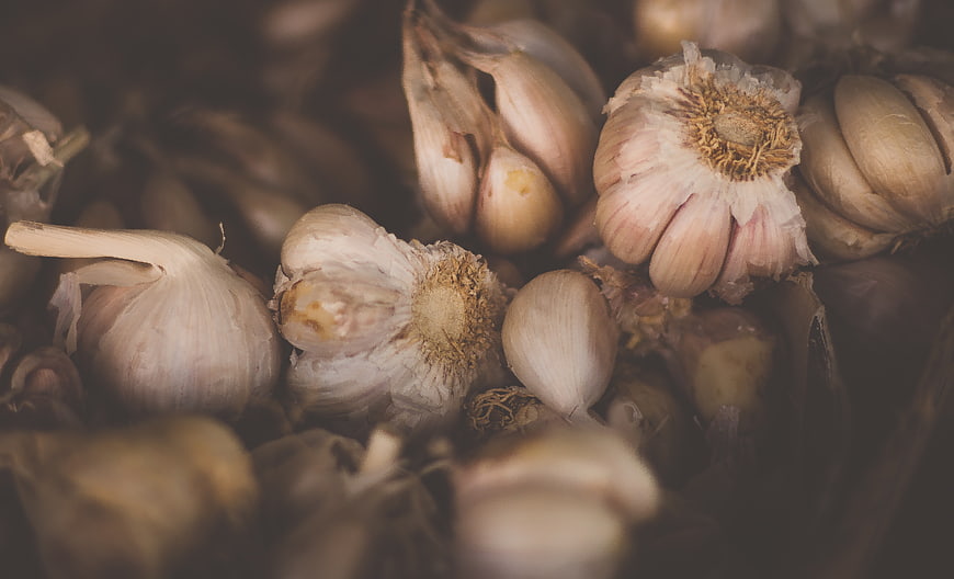 Close-up of fresh garlic bulbs and cloves in rustic bowl