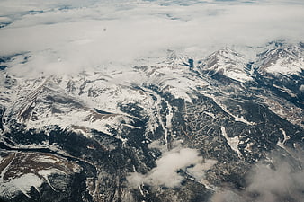 Aerial view of snow-covered Rocky Mountains with clouds