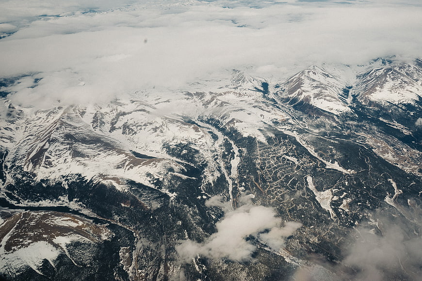 Aerial view of snow-covered Rocky Mountains with clouds