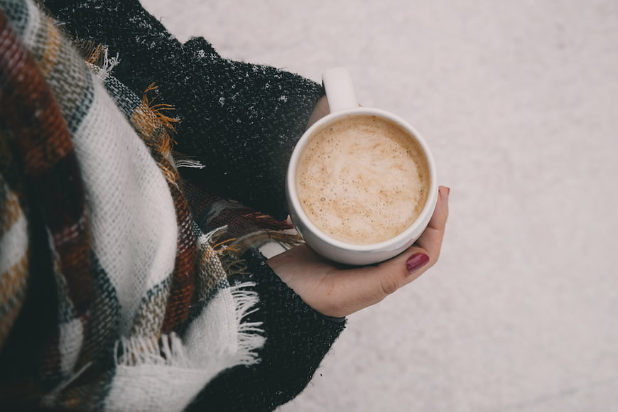 Woman holding hot coffee cup in snowy winter