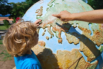 Child pointing at large outdoor globe map of Europe