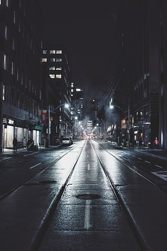 Moody Night City Street with Tram Tracks and Wet Pavement