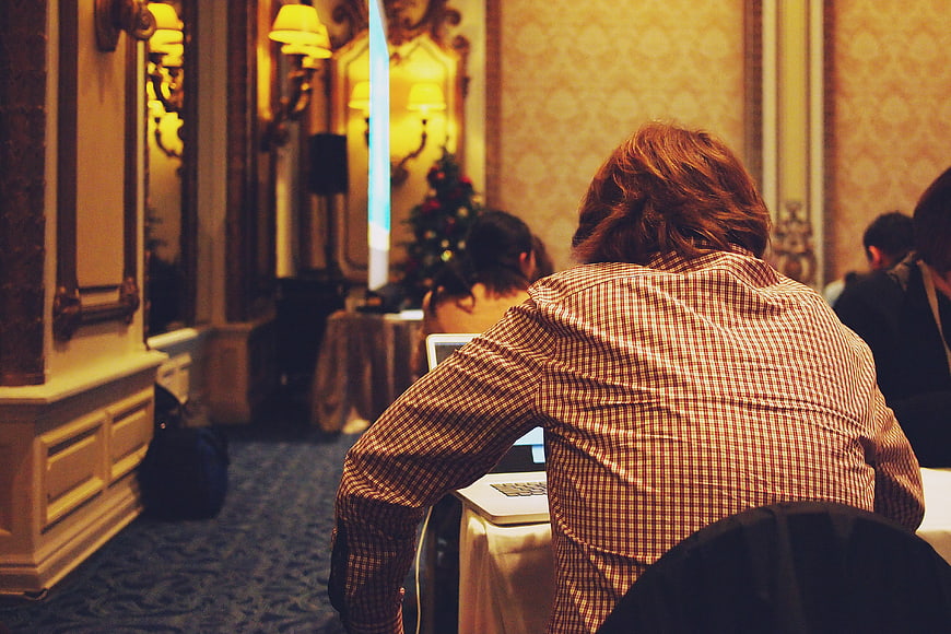 Man working on laptop at conference in ornate room