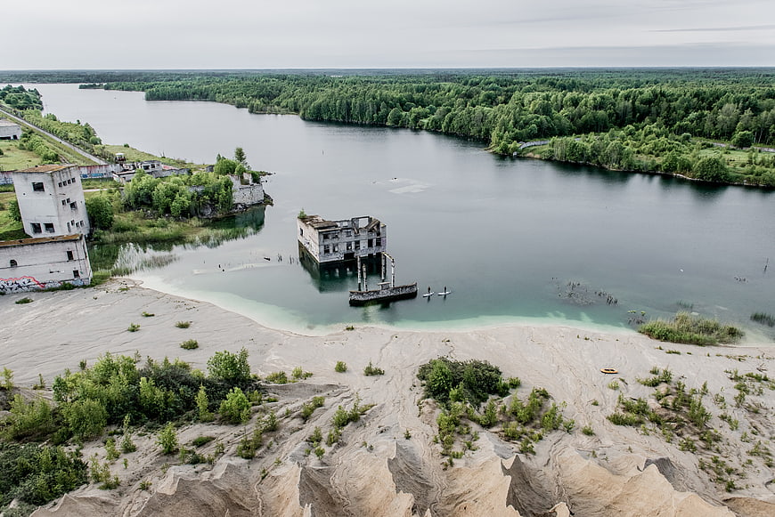 Aerial view of abandoned buildings submerged in a flooded quarry lake