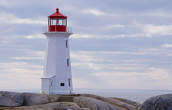 White Lighthouse With Red Roof On Rocky Coastline