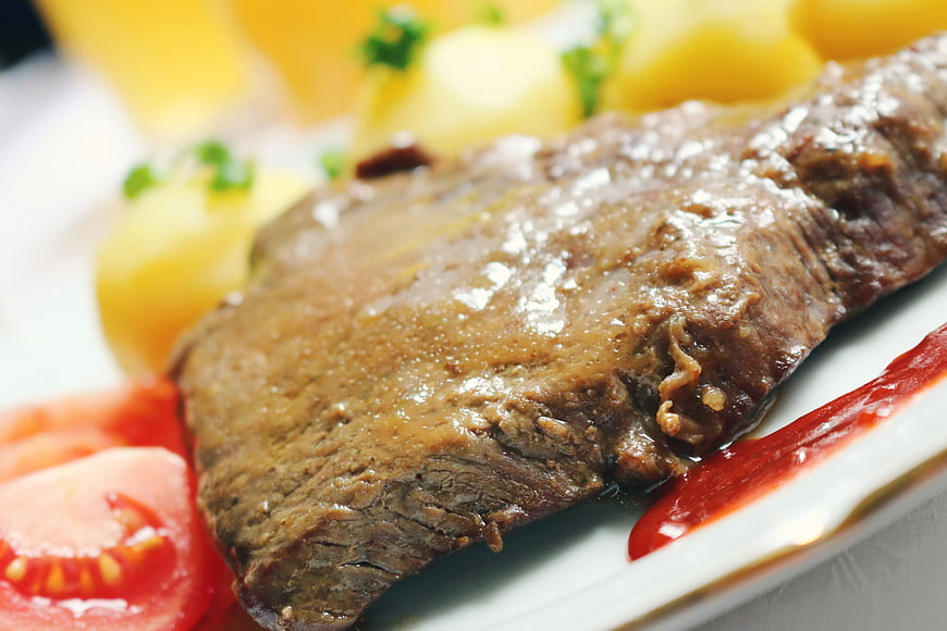 Close-up of roasted beef steak with potatoes and tomato