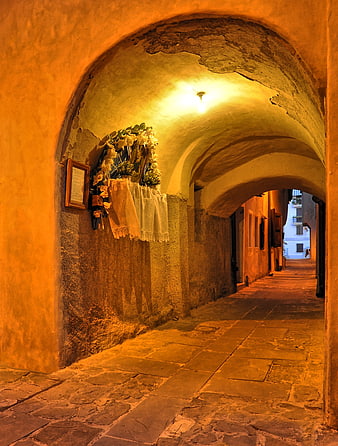 Illuminated Arched Stone Passage With Religious Shrine In Historic Italian Town