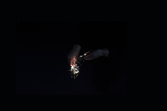 Hands lighting a sparkler in the dark night