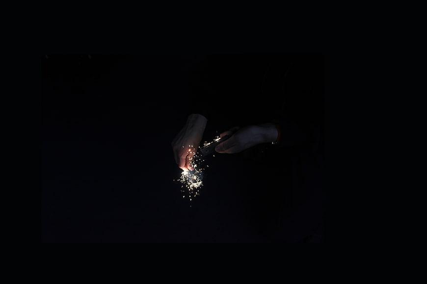 Hands lighting a sparkler in the dark night
