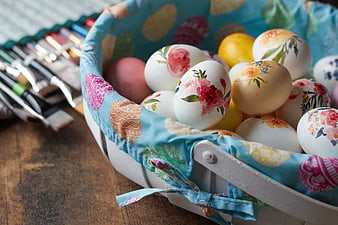 Hand-painted Easter eggs in a floral basket with brushes