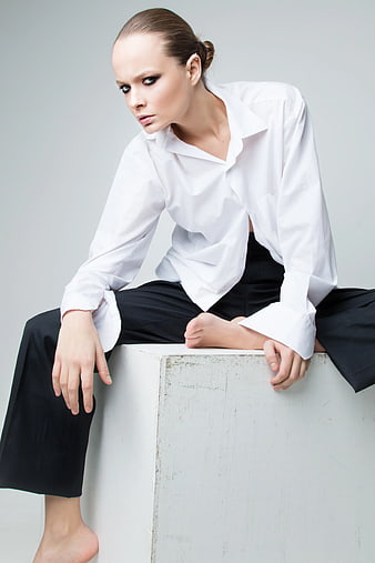 Fashionable Woman in White Shirt Sitting on Cube