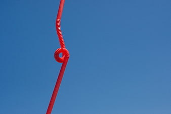 Red Coiled Cable Against Blue Sky Background