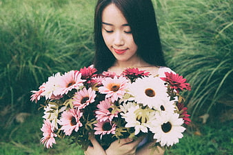 Asian woman holding bouquet of pink and white gerbera daisies