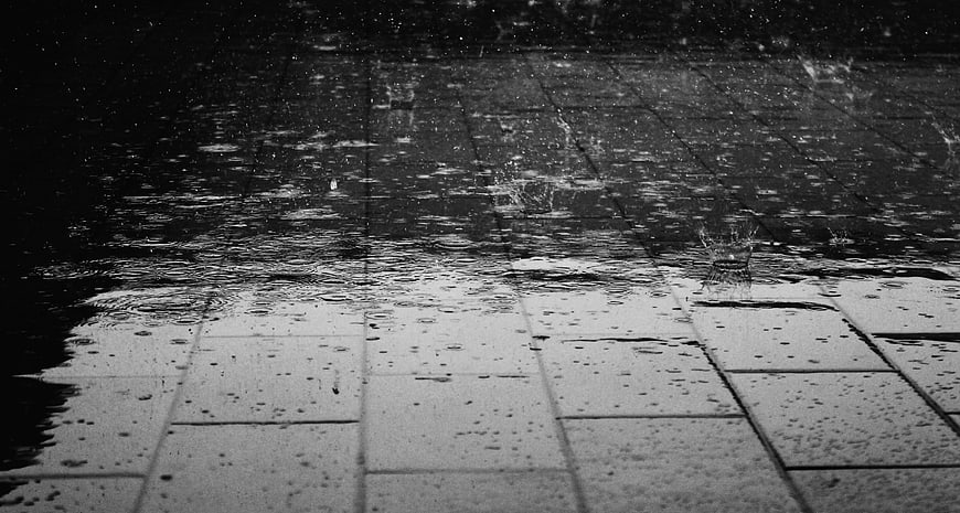 Black and white raindrops splashing on wet pavement