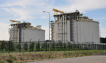 Large Industrial Gas Storage Tanks With Yellow Piping And Security Fence