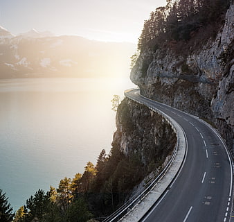 Winding Mountain Road Along Cliffside Lake at Sunset