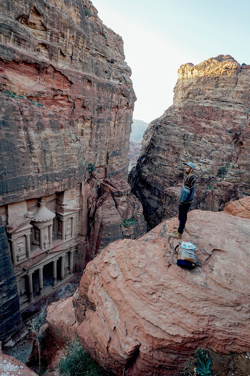 Man standing on rock overlooking ancient Petra Treasury