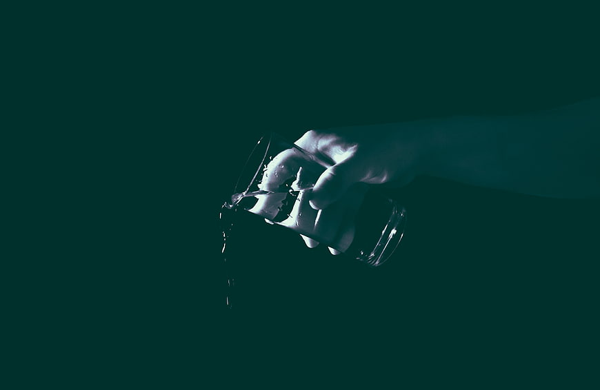 Hand Pouring Water from Glass in Dark Teal Atmosphere