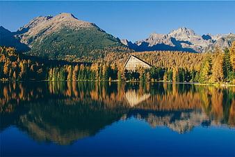 Modern A-Frame Hotel Reflected in Alpine Lake with Autumn Mountains