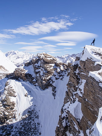 Woman standing on snowy mountain peak with blue sky