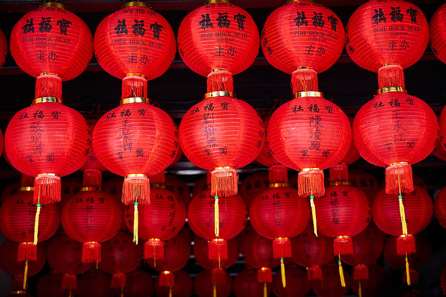 Rows of red Chinese lanterns with calligraphy hanging at night