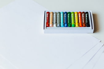 Box of colorful oil pastels on white paper