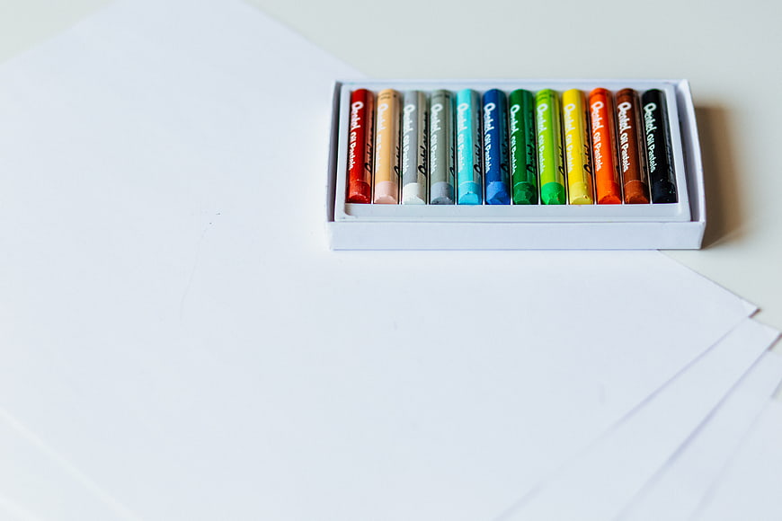 Box of colorful oil pastels on white paper