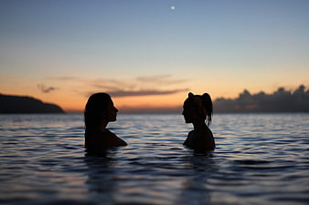Silhouette of Two Women Swimming in Ocean at Sunset