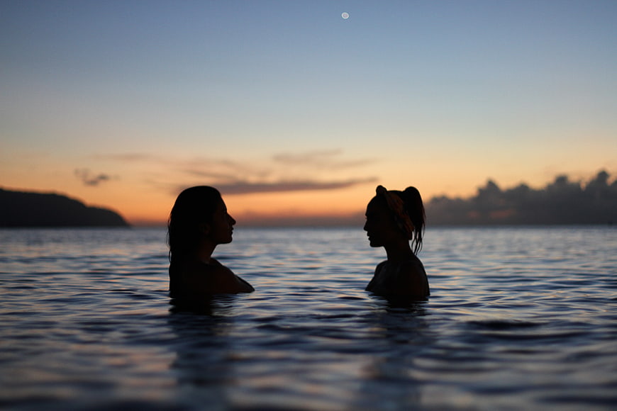 Silhouette of Two Women Swimming in Ocean at Sunset