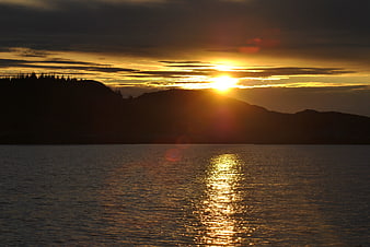Golden sunset over calm sea with silhouetted mountains