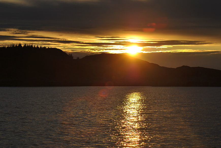Golden sunset over calm sea with silhouetted mountains