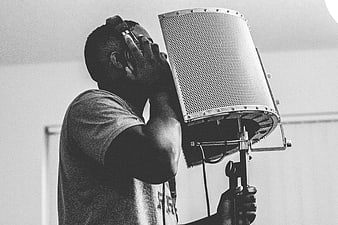 Black and white photo of a man singing into a studio microphone