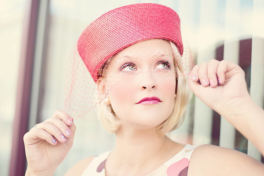 Blonde woman in pink vintage hat with veil