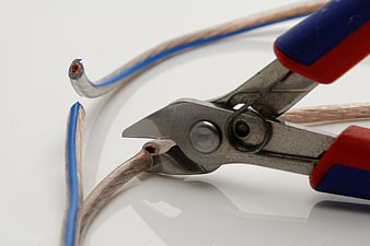 Close-up of wire cutters cutting a blue and white electrical cable