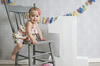 Cute baby girl celebrating first birthday on vintage chair