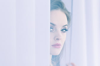Woman Peeking Through White Curtains Close Up