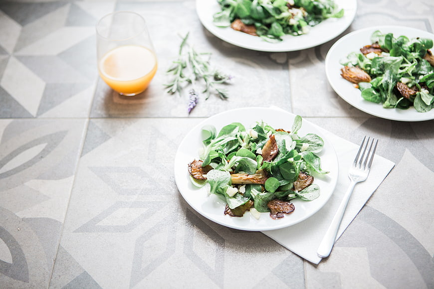 Healthy green salad with mushrooms and orange juice on table