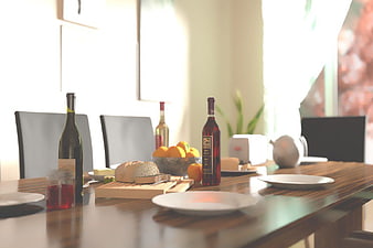 Set dining table with wine, bread, and fruit in bright kitchen