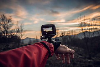 Action camera on wrist mount filming sunset mountain landscape