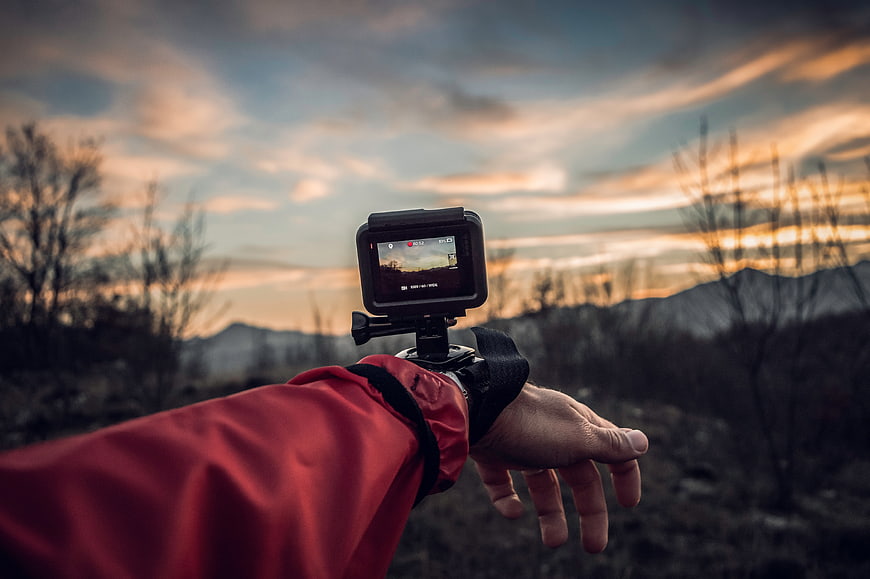 Action camera on wrist mount filming sunset mountain landscape