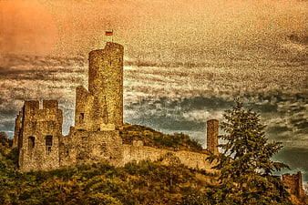 Dramatic medieval stone castle ruins on a hill with German flag