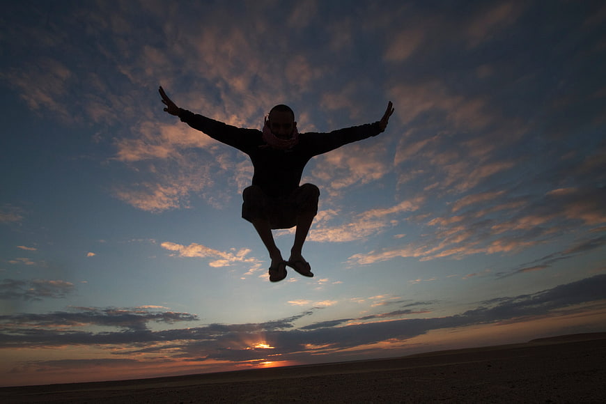 Silhouette of Man Jumping Joyfully Against Dramatic Sunset Sky