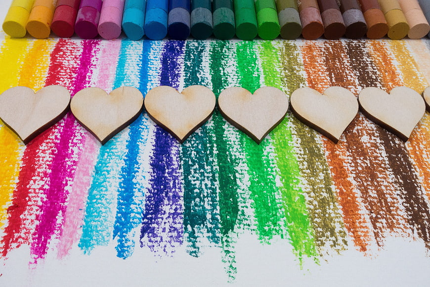 Wooden hearts on colorful chalk rainbow stripes background