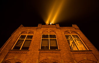 Brick building facade illuminated by searchlights at night