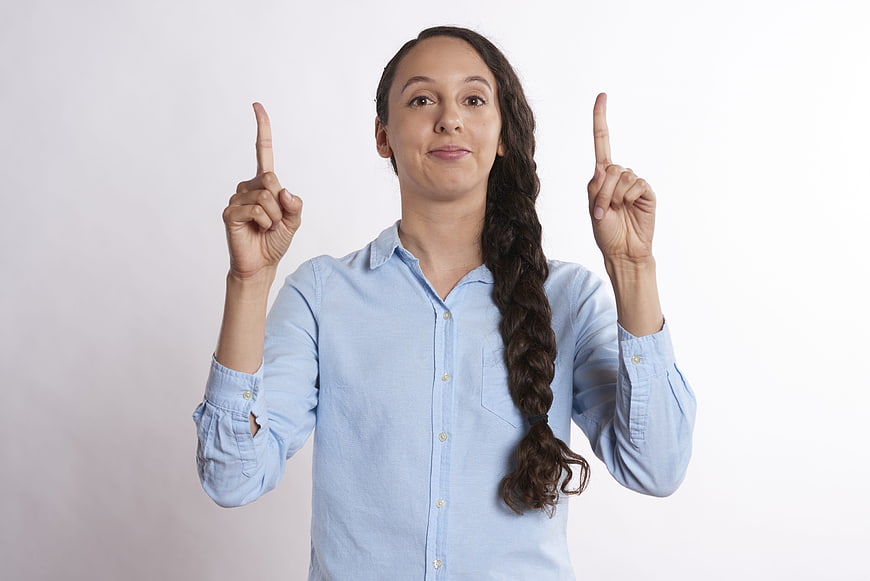Woman Pointing Up with Both Index Fingers on White Background