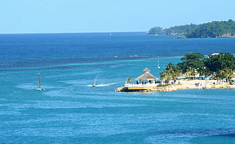 Tropical beach landscape with gazebo, jet ski, and sailboat in Jamaica