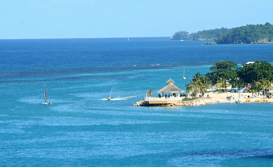 Tropical beach landscape with gazebo, jet ski, and sailboat in Jamaica