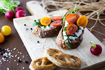 Healthy Bruschetta with Cherry Tomatoes, Arugula, and Pretzels on Wooden Board