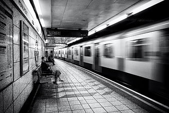 Woman waiting on London Underground platform with passing train